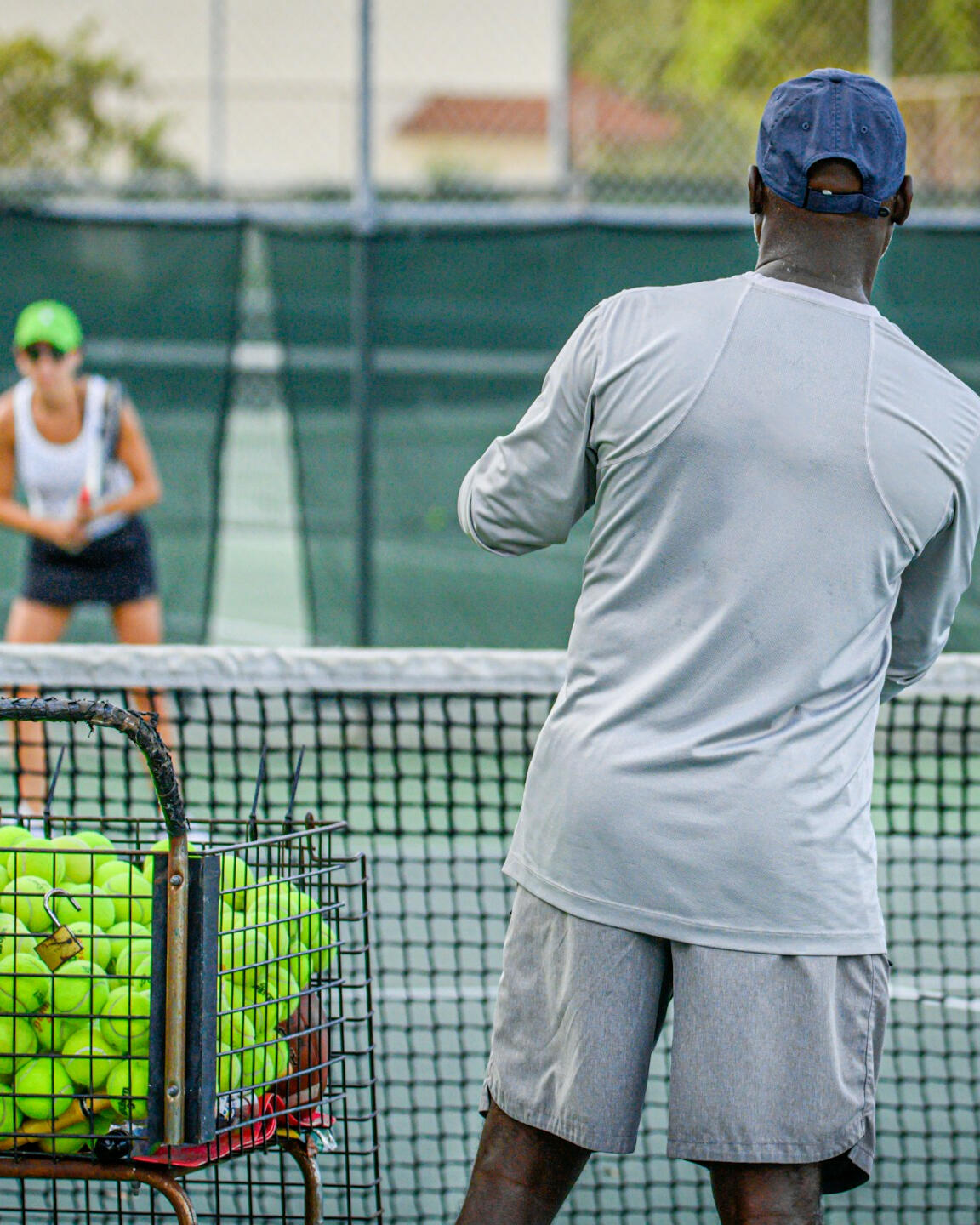 Tennis coach preparing to feed ball to female player — technical refinement and athlete-coach trust