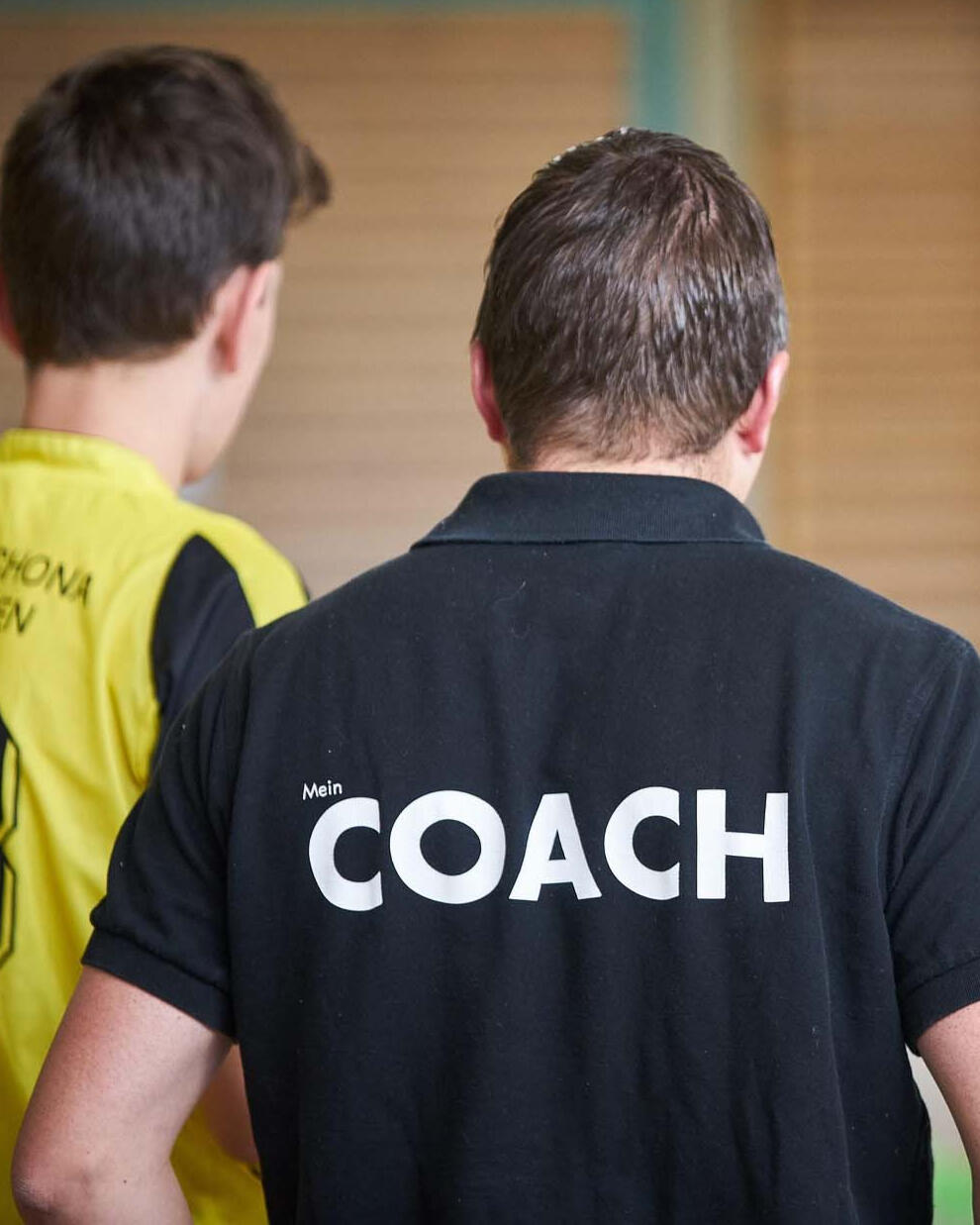 Coach mentoring young athlete indoors — early development, guidance, and mental foundation building