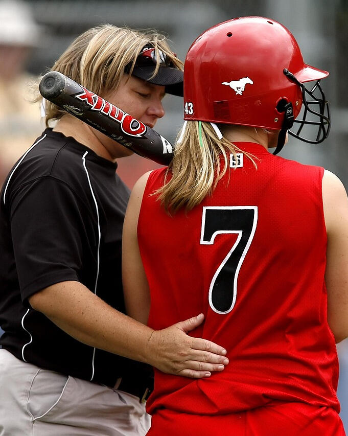 Softball coach talking to female player — supporting confidence, development, and emotional resilience
